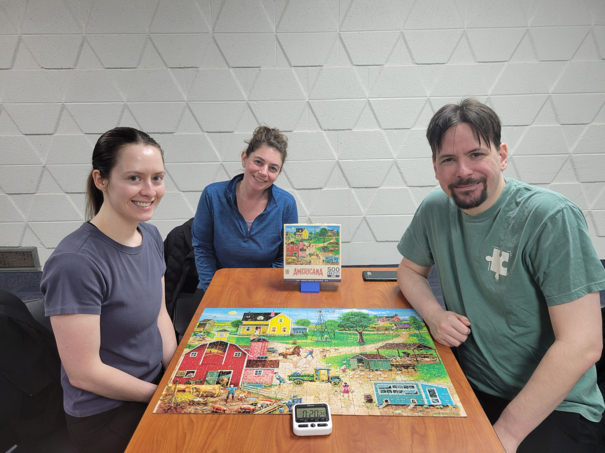 The winners of the Adult Jigsaw Puzzle Competition, a three-member team, posing around their finished 500-piece puzzle.